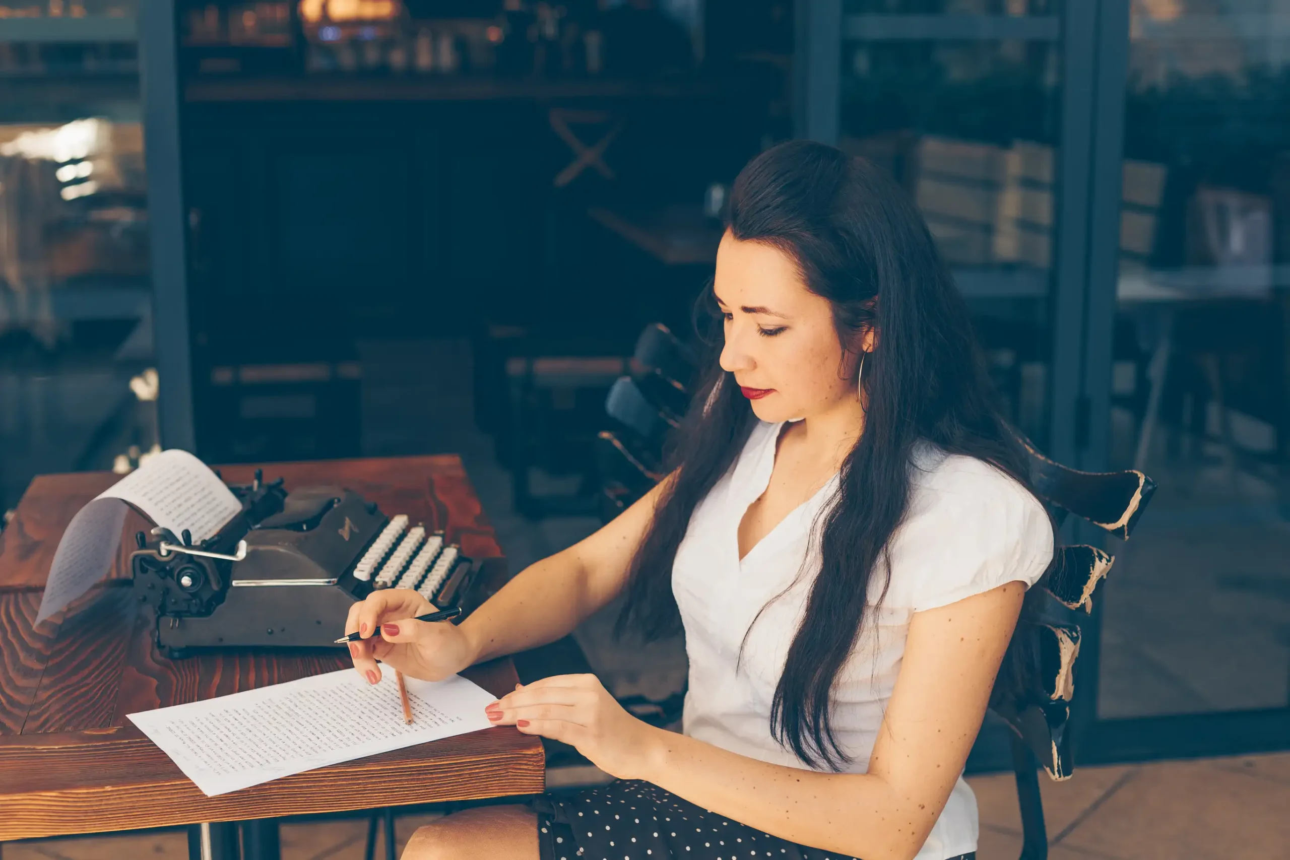 woman sitting writing paper cafe terrace white shirt daytime